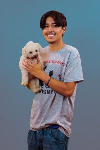 A man holding a small white dog in his arms.
